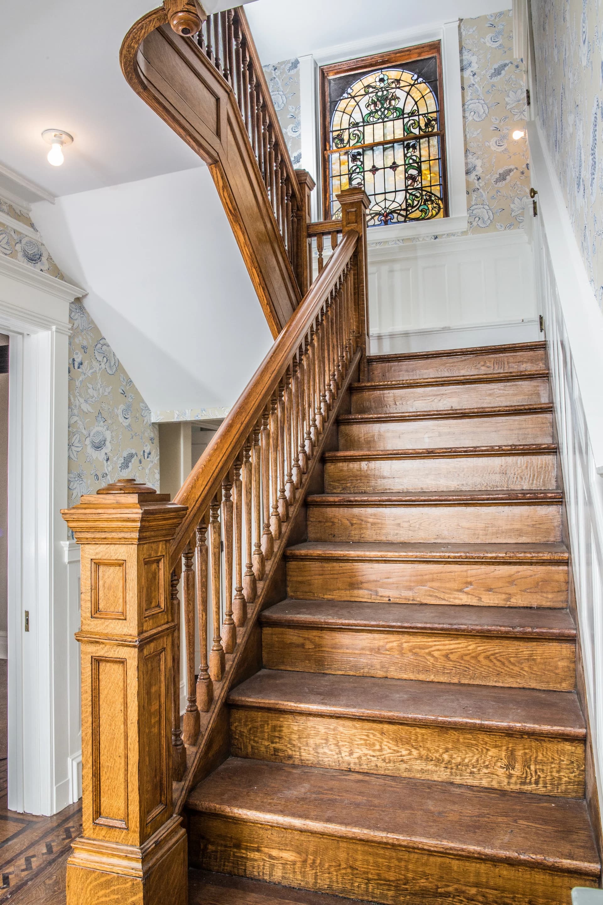 Restored historic staircase, woodwork, and stained-glass window